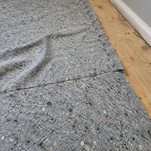 Carpet padding stapled over plywood subfloor during carpet installation