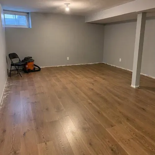 Engineered floor in basement before baseboards, ahead of engineered hardwood installation