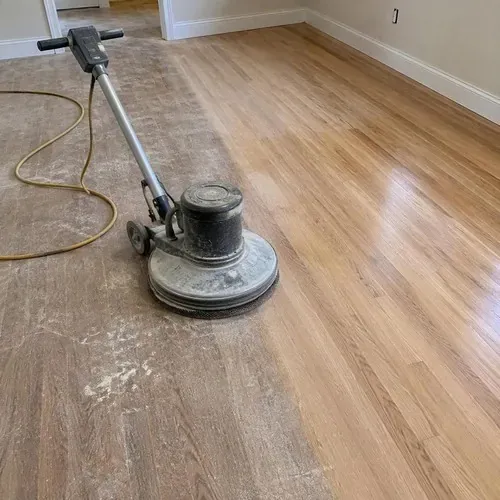 Buffer with screen pad on hardwood floor during hardwood floor sanding and refinishing
