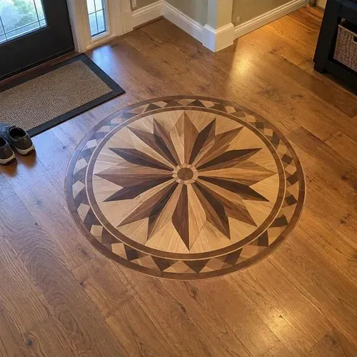 Custom wood medallion inlay in foyer floor during herringbone and parquet floor installation