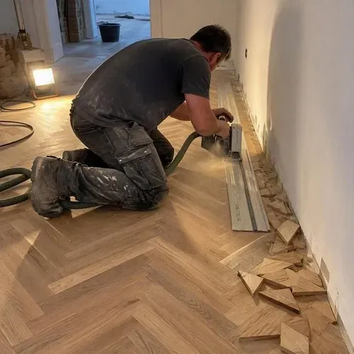 Installer track-sawing herringbone ends along wall during herringbone and parquet floor installation