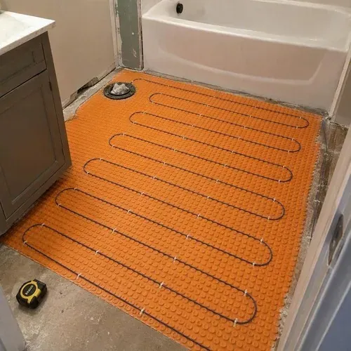 Electric heating cable laid across bathroom membrane during radiant heated floor installation