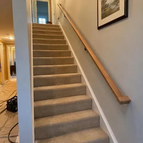 Carpeted stairs with new wood handrail after stair and railing installation