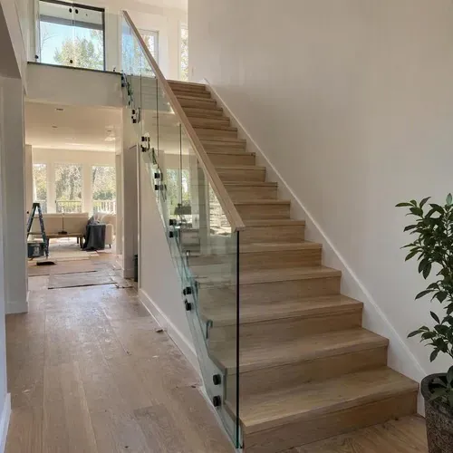 Finished wood stairs with glass panel railing after stair and railing installation