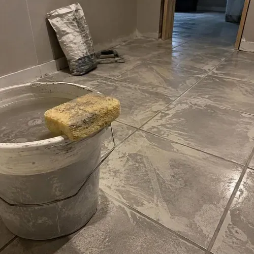 Grout sponge and bucket on fresh grout during ceramic and porcelain tile installation
