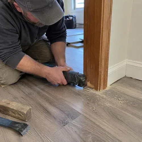 Laminate cut around door frame with oscillating tool during vinyl and laminate flooring installation