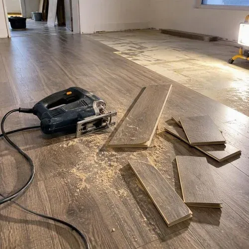 Offcuts and jigsaw in half-finished laminate room during vinyl and laminate flooring installation
