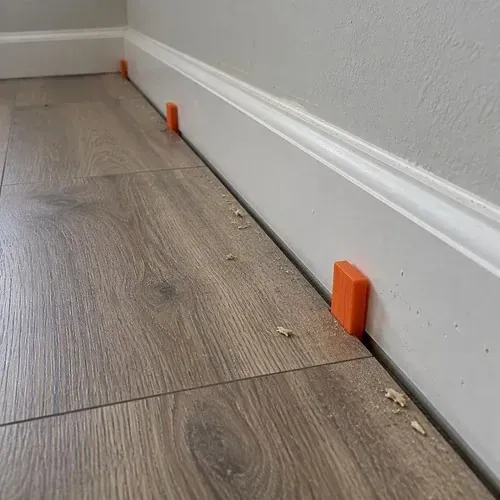 Plastic spacers along wall at laminate edge during vinyl and laminate flooring installation