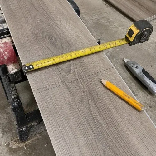 Tape measure and pencil marks on vinyl plank during vinyl and laminate flooring installation